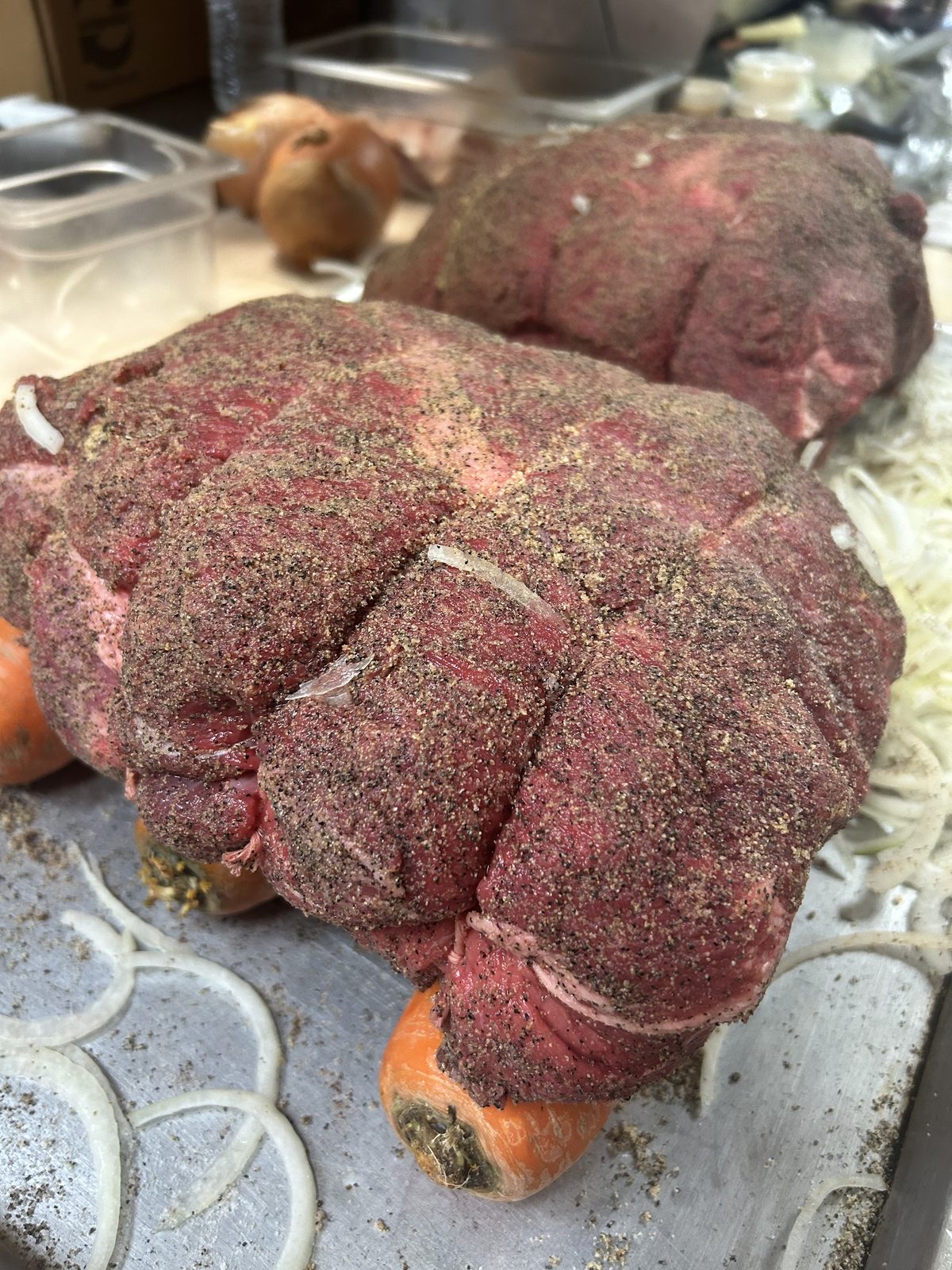 Home-cooked roast beef being prepared with fresh seasonings, onions, and carrots
